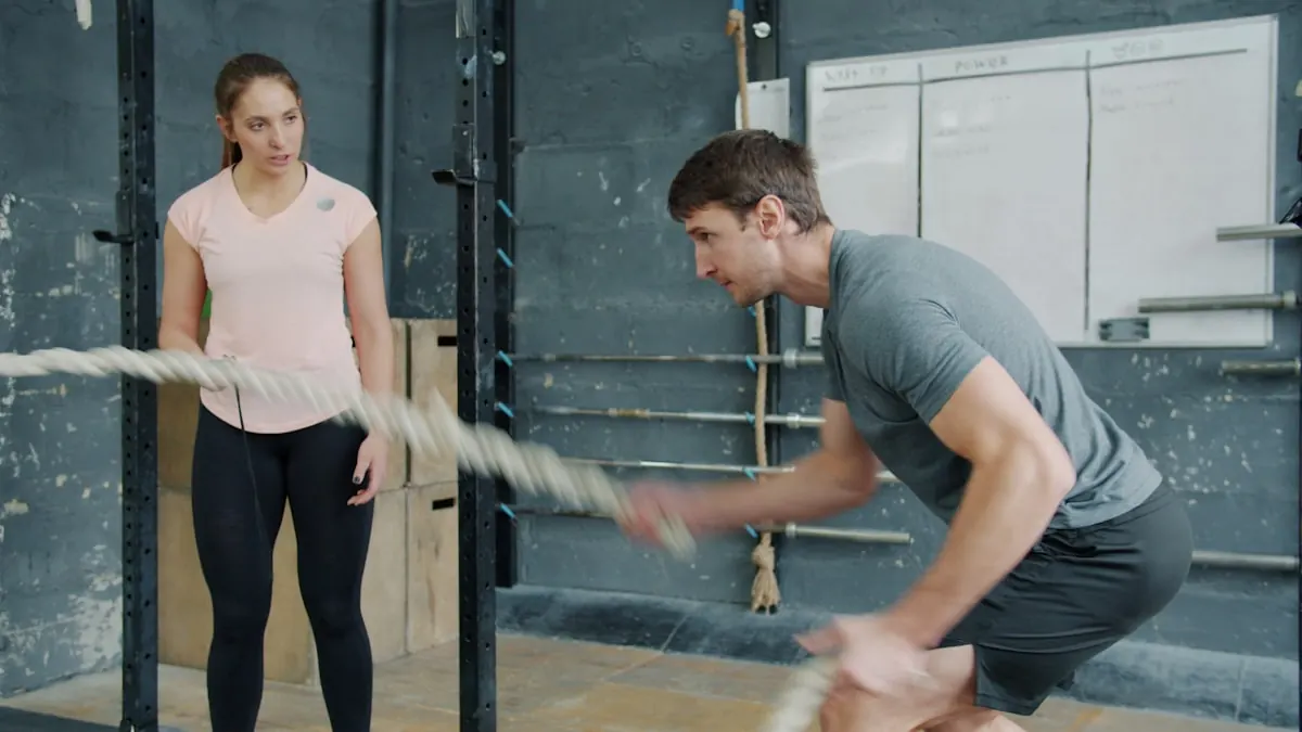 Two members working battle ropes side by side in a bright studio