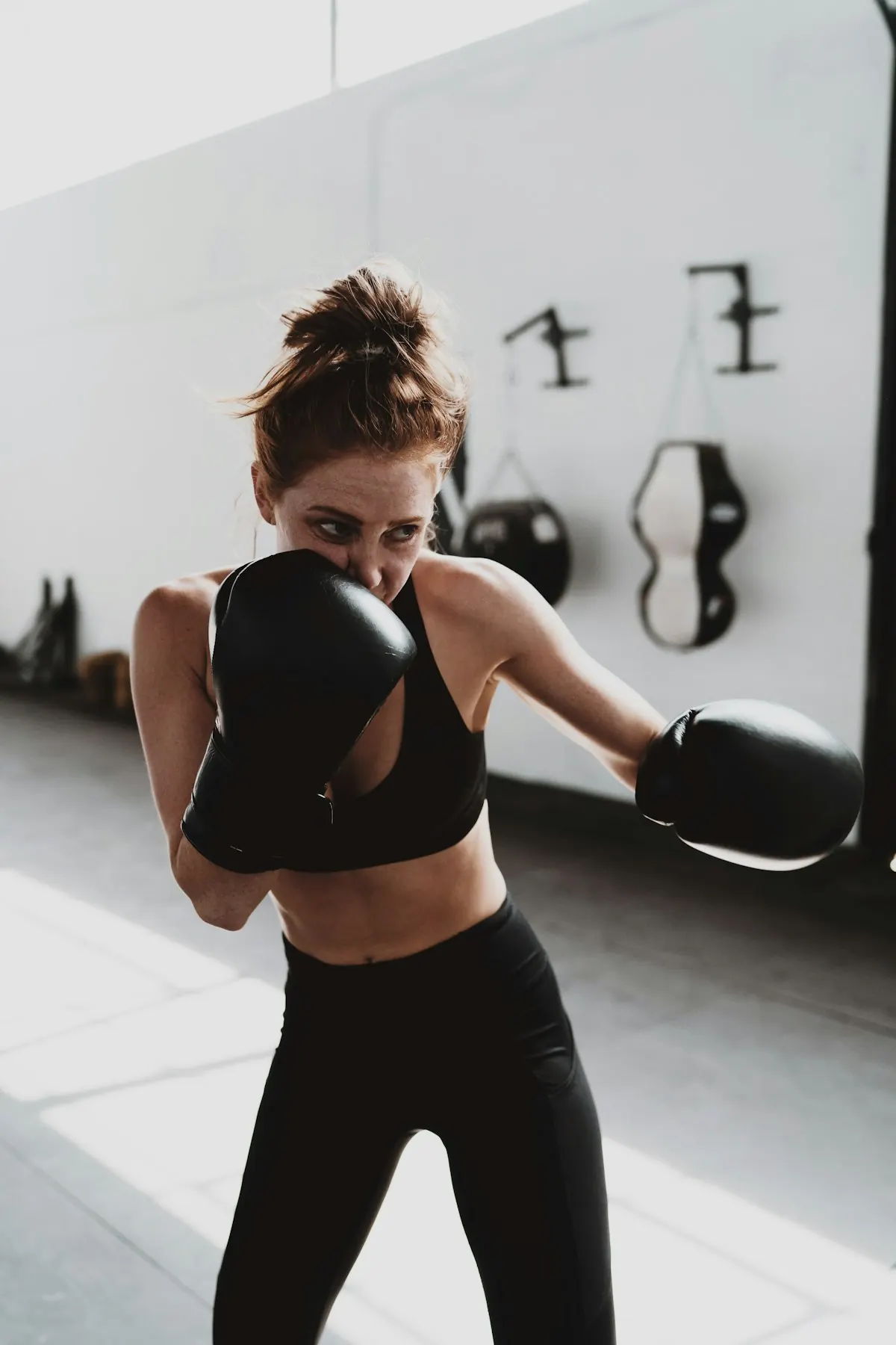 Member in boxing gloves, guard up, in a bright white studio