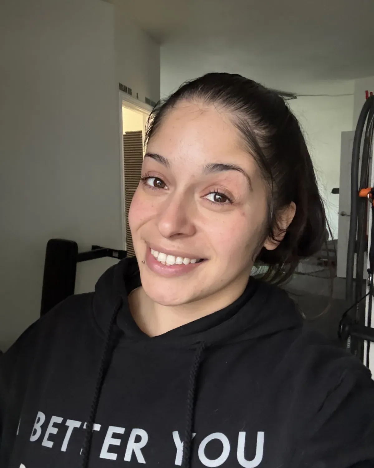 Member in an A Better You hoodie smiling in the gym
