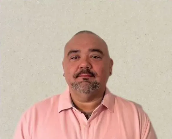 Member smiling in a pink polo shirt