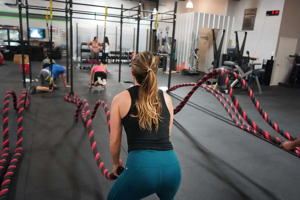 Woman driving battle ropes during a coached strength class